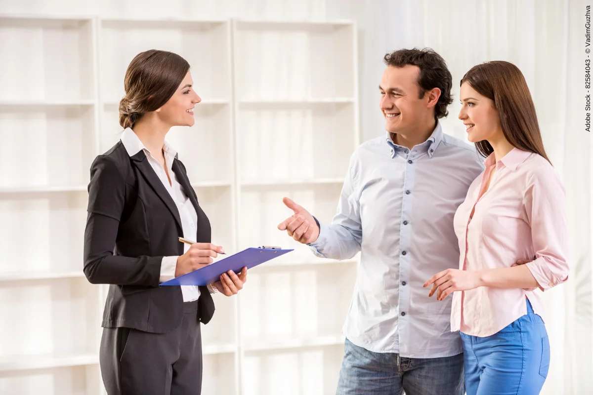A couple consulting a real estate agent during a property investment discussion in an office setting