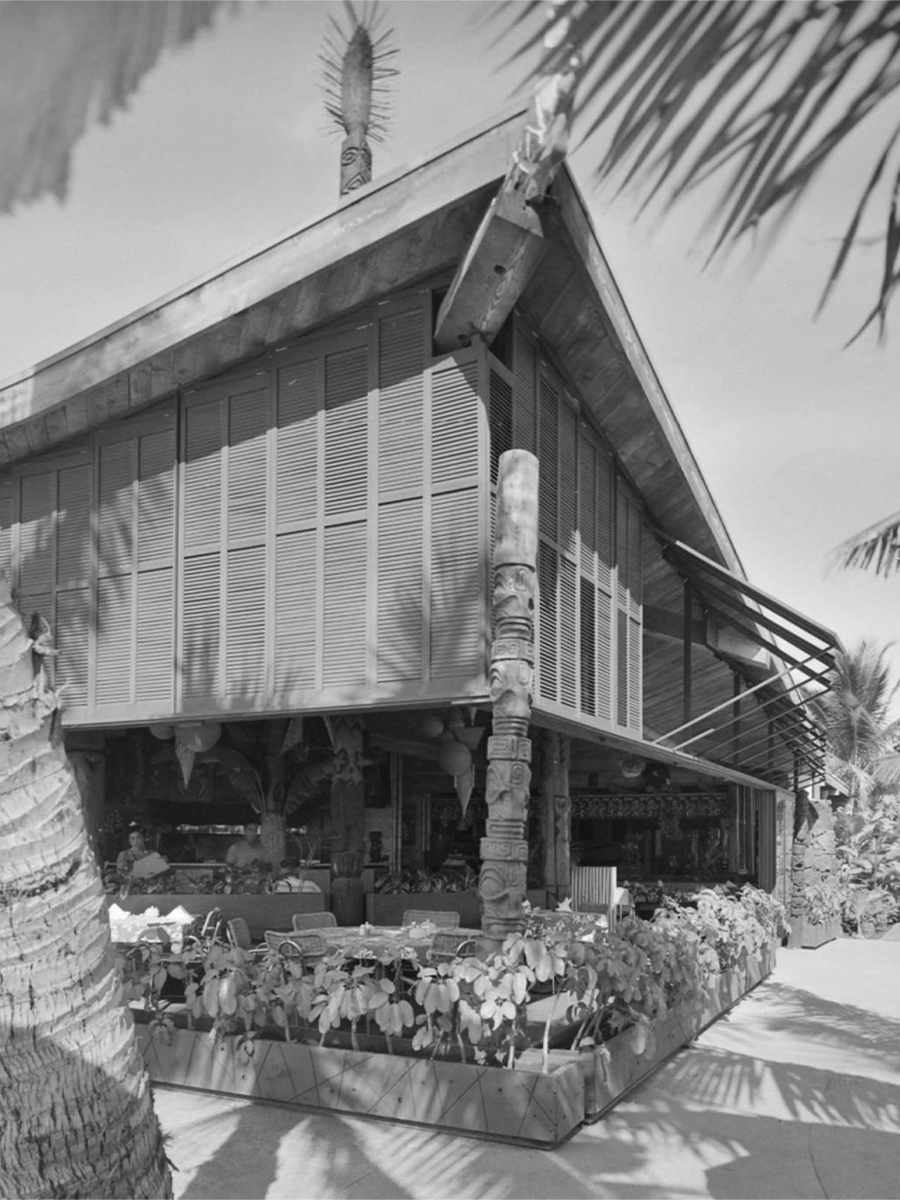 Vintage tiki bar exterior of Tahitian Lanai in Waikiki featuring traditional carved tiki totem poles and tropical ambiance