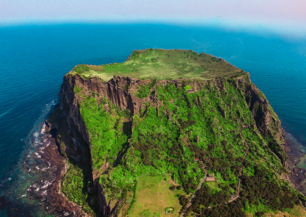 A scenic aerial view of Seongsan Ilchulbong (Sunrise Peak) on Jeju Island, known for its stunning volcanic crater and hiking trails with panoramic ocean views