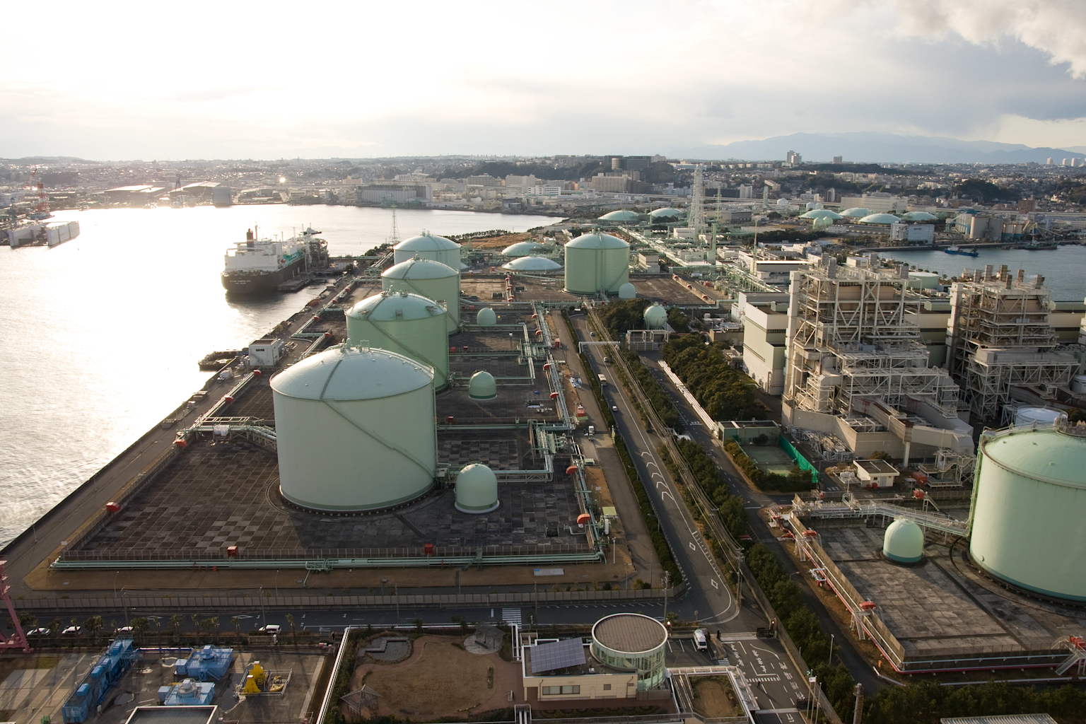 Aerial view of a liquefied natural gas (LNG) terminal with storage tanks and an LNG tanker ship docked nearby