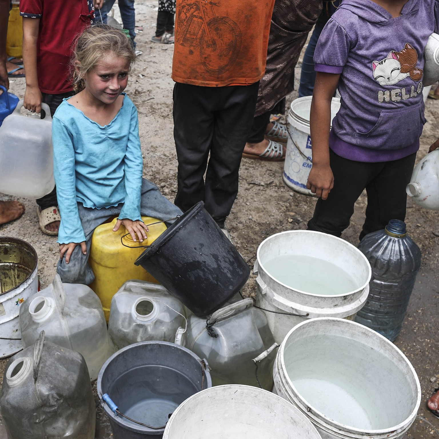Children and residents collecting water in containers amid a water scarcity crisis