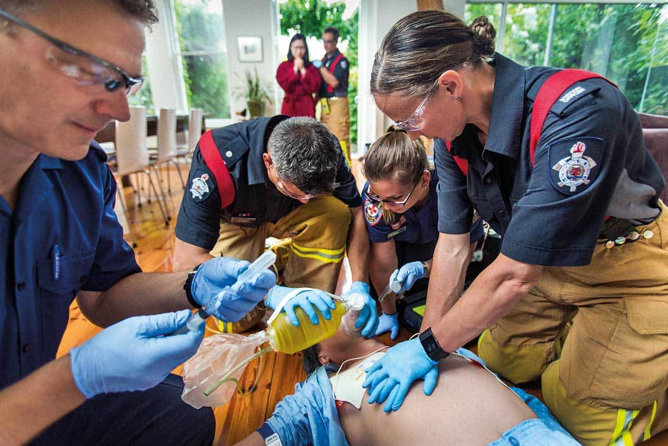 Paramedics performing advanced cardiac life support during a cardiac emergency in a home setting