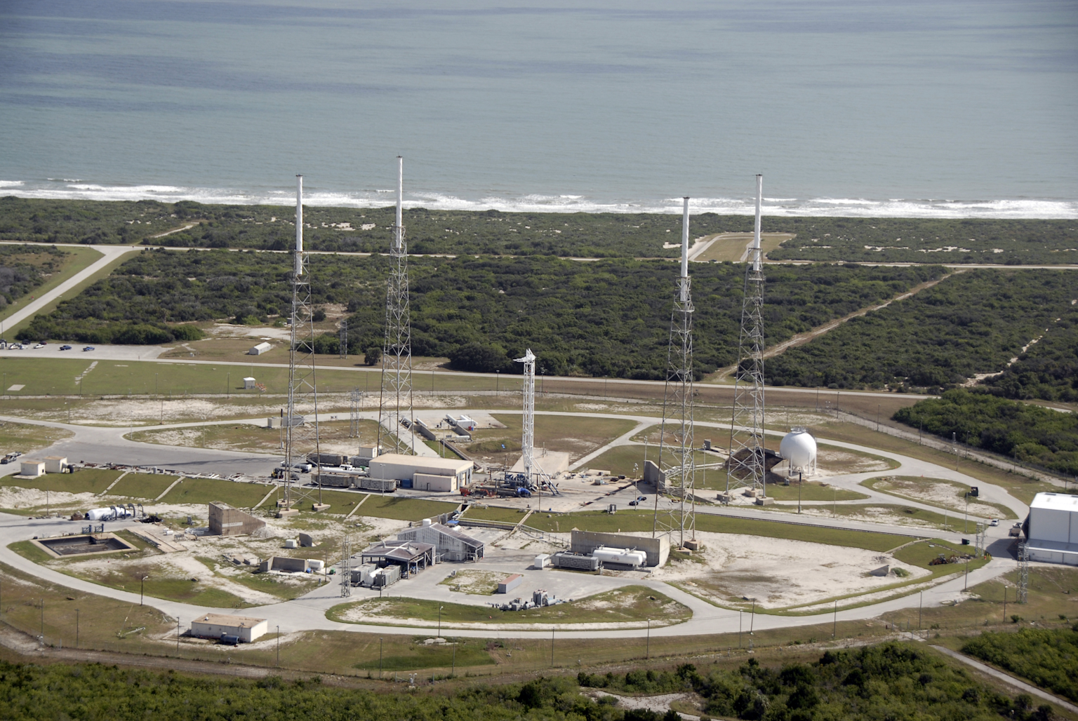Aerial view of SpaceX rocket launch facility showing launch towers and support infrastructure along the coast