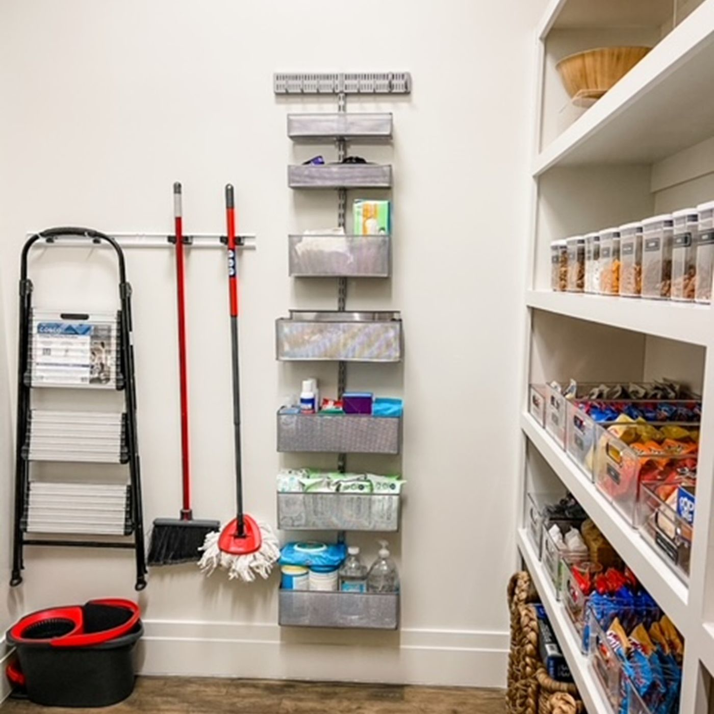 Organized home cleaning supplies including mops, brooms, cleaning products, and pantry containers arranged neatly for efficient household maintenance