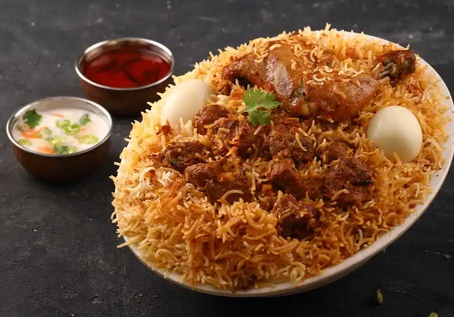 Authentic Hyderabadi biryani served with boiled eggs, raita, and red chutney in a traditional presentation