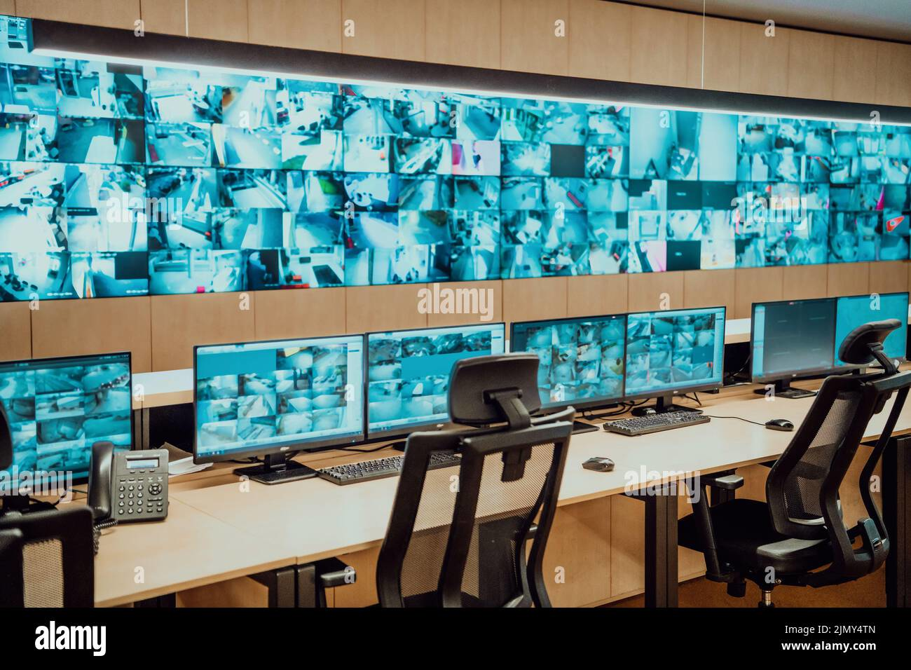 Empty security control room with multiple monitors displaying surveillance camera feeds.