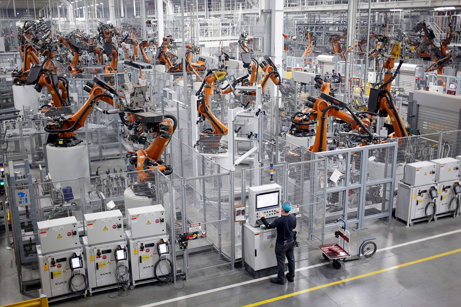 Automated industrial robots operating in a factory with minimal human intervention, illustrating manufacturing job automation trends
