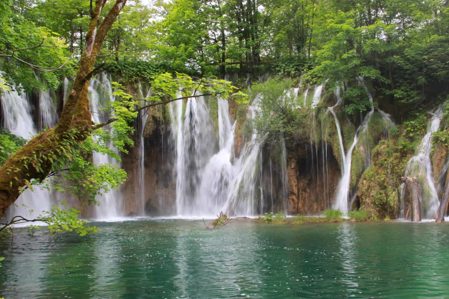 Cascading waterfalls at Plitvice Lakes, Croatia, surrounded by vibrant green forest creating a magical, fairytale atmosphere