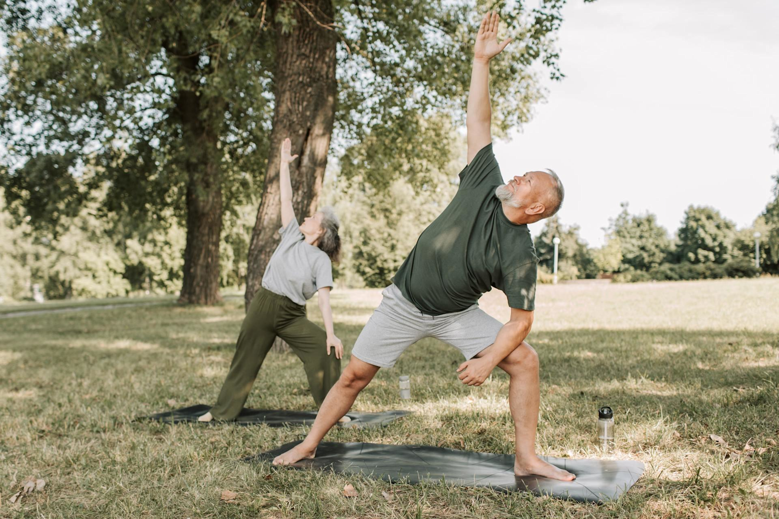 Elderly man and woman practicing yoga outdoors promoting active and healthy aging