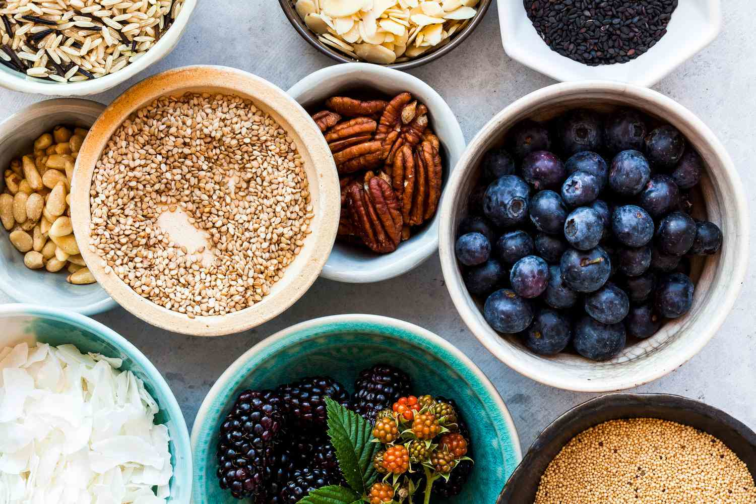 Various nutrient-rich plant foods including nuts, seeds, berries, and coconut flakes in bowls