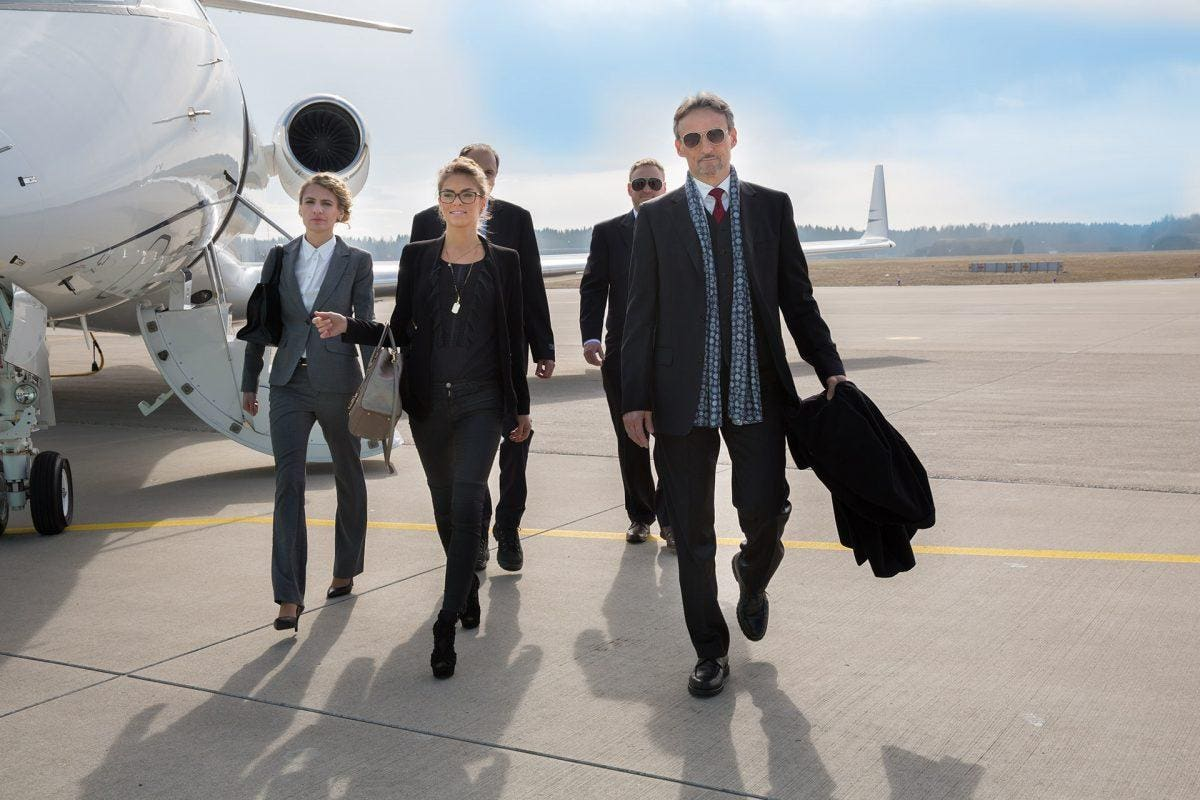 A group of professionals walking away from a private jet, illustrating luxury personalized travel experiences