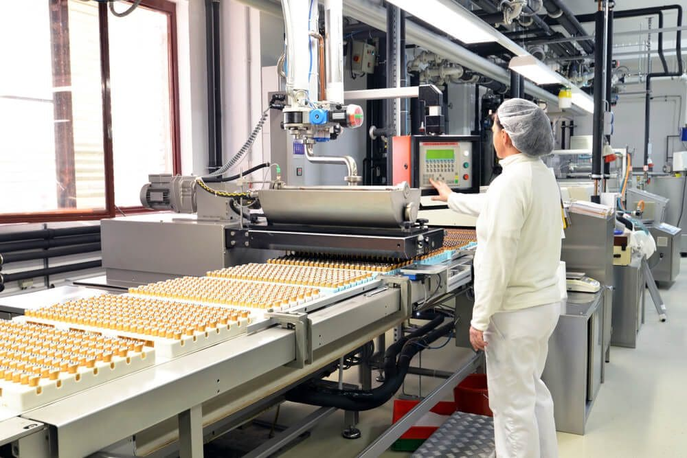 Worker operating automated machinery in a clean industrial food processing plant