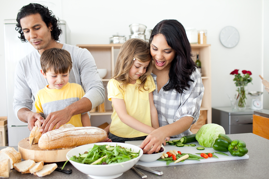 A family preparing a healthy meal together in the kitchen with fresh vegetables and bread