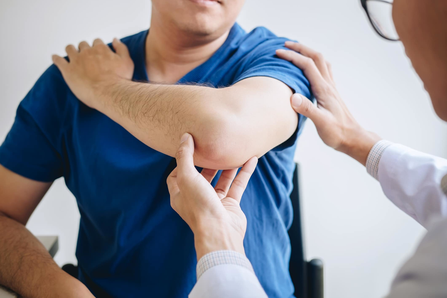 A sports medicine doctor examining an athlete's elbow injury during a clinical consultation