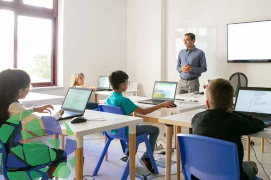 A classroom showcasing digital learning with students using laptops and a teacher guiding the lesson