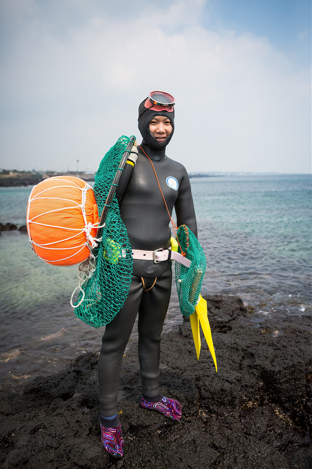 Traditional Haenyeo female free diver from Jeju Island with diving gear on rocky shore