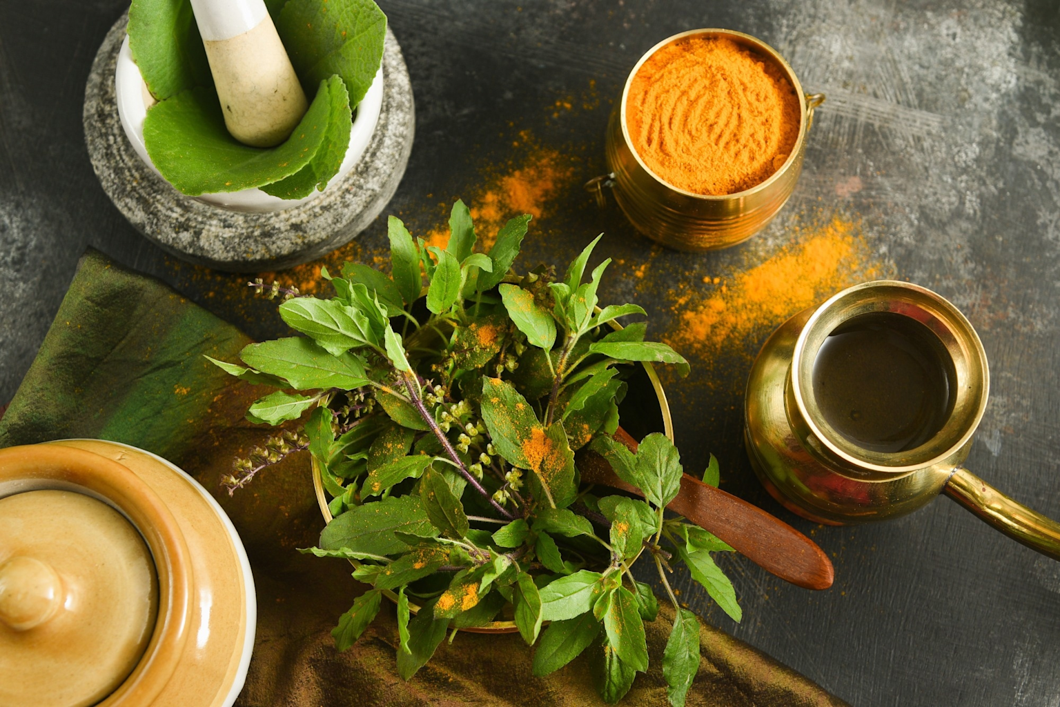 Fresh Ayurvedic herbs, turmeric powder, and traditional tools for herbal medicine preparation