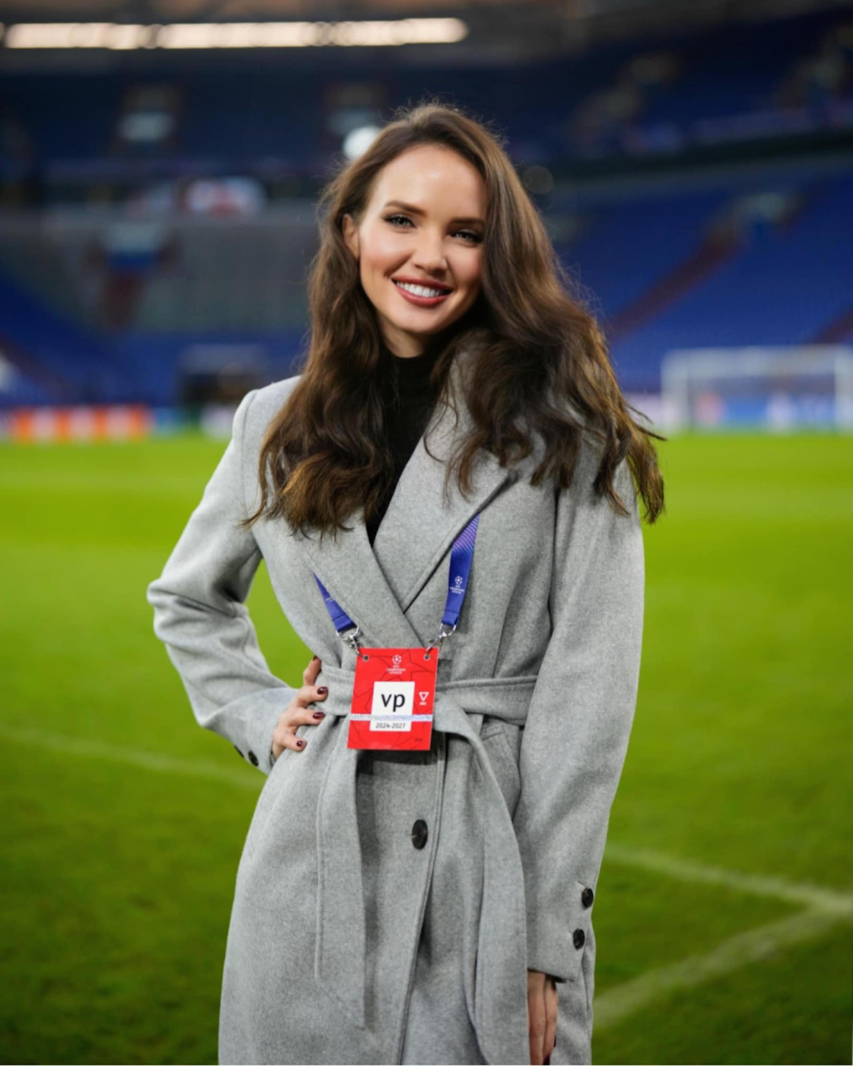 A female sports journalist with a media pass standing on a football field during a UEFA Champions League event