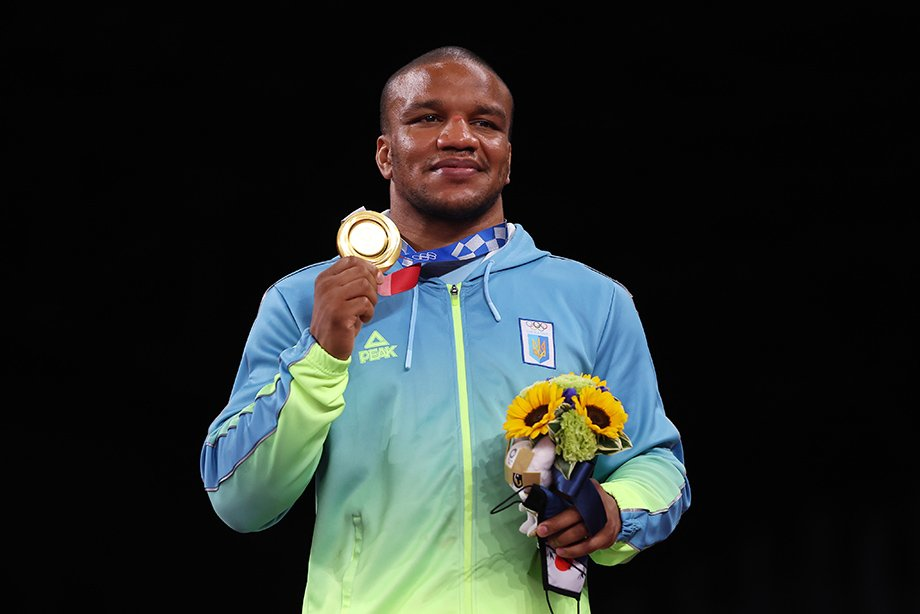 Ukrainian Olympic athlete holding a gold medal and a bouquet of flowers