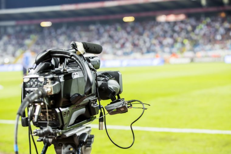 Professional video camera filming a live sports event illustrating sports journalism in action