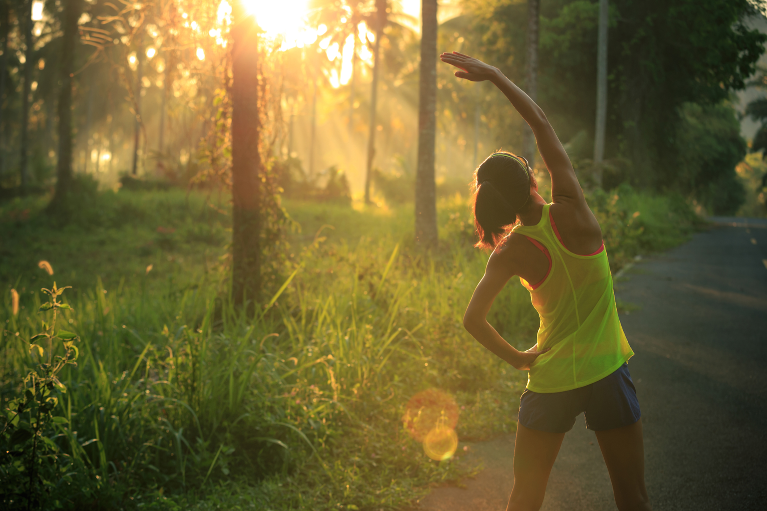 A person stretching outdoors in the morning sunlight, illustrating early workout aligned with biological rhythms