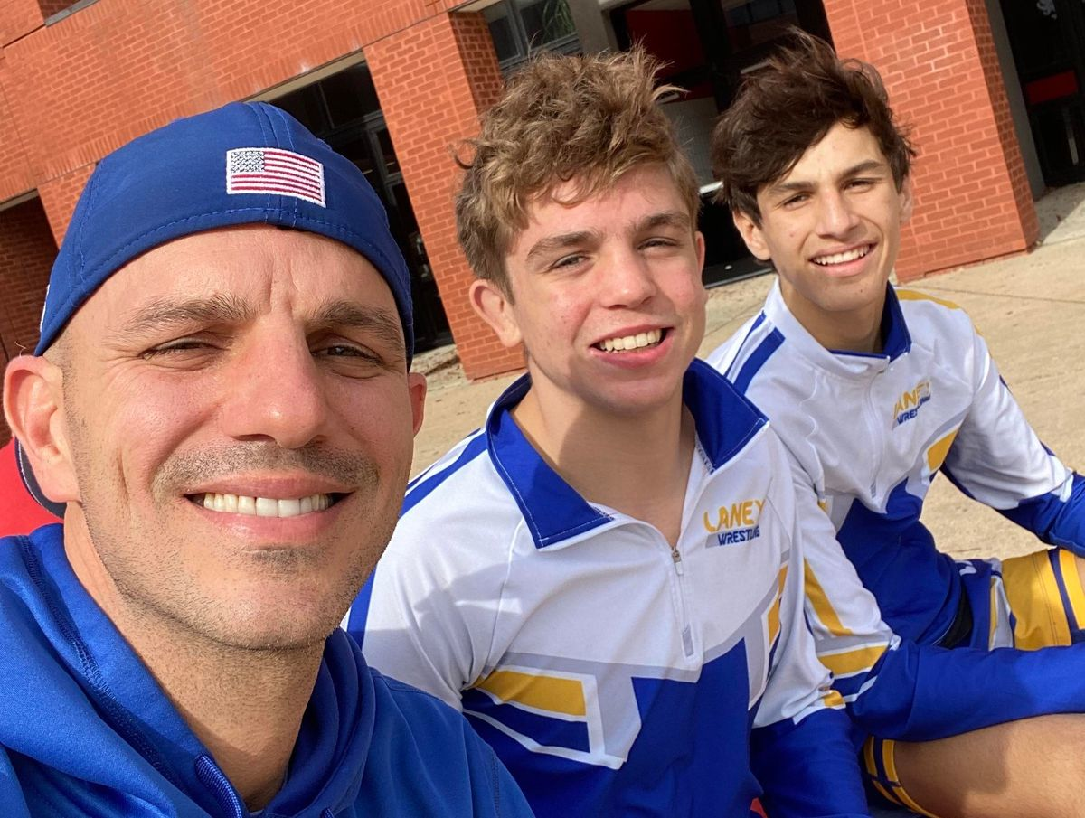 Youth wrestlers and a coach sitting outdoors showing a supportive sports environment