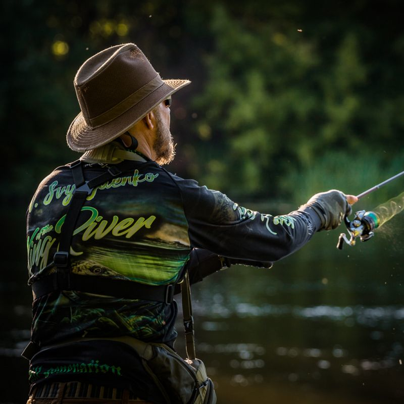 Fisherman casting a line in a serene natural setting, illustrating the outdoor fishing experience