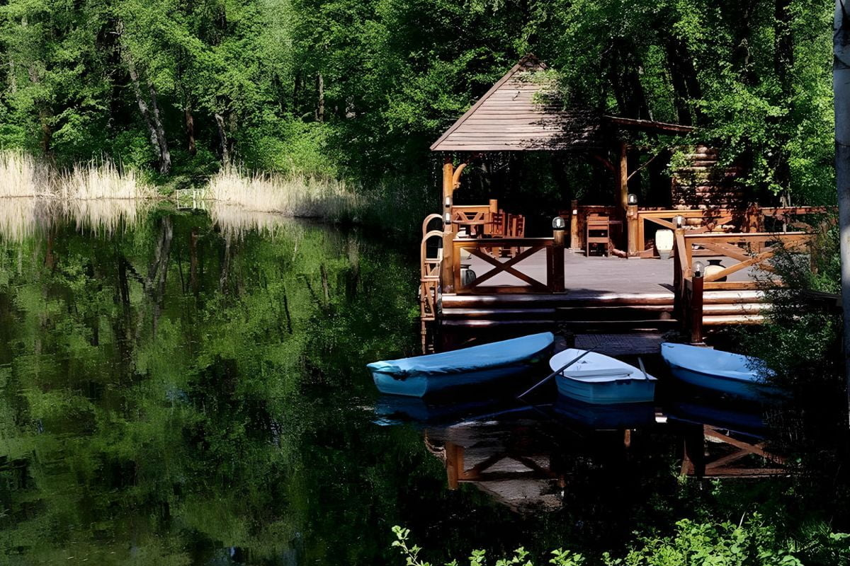 A peaceful lakeside wooden pier with boats surrounded by lush greenery, ideal for fishing and outdoor tourism