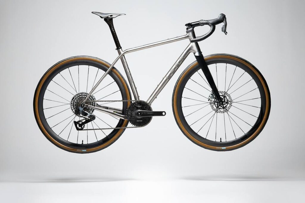 The Leon LaRage titanium gravel bike features a sporty geometry with a brushed titanium frame and carbon fork, designed for stable and comfortable long-distance rides