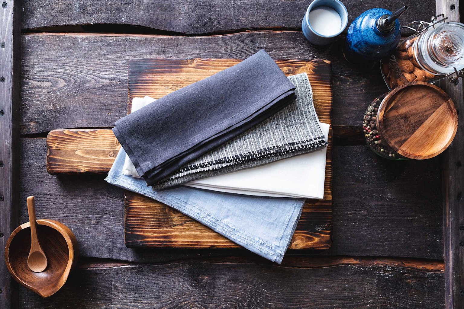Rustic food photography props and folded linen napkins arranged on a wooden surface to demonstrate styling and composition techniques.