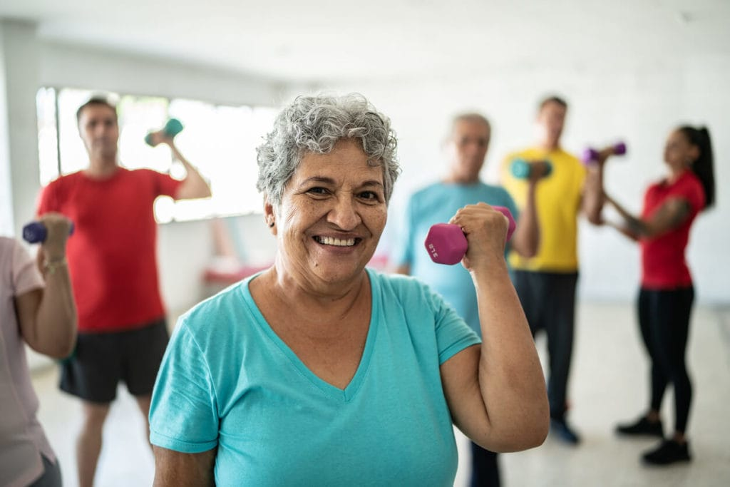 Elderly individuals engaging in group exercise with dumbbells to promote healthy aging and an active lifestyle