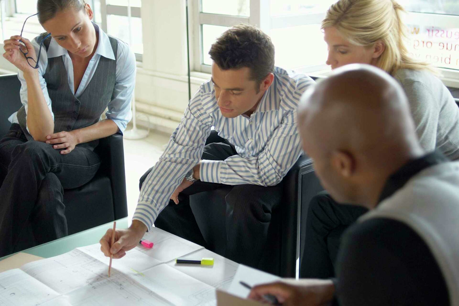 A team collaborates in a corporate meeting, examining documents and planning strategies