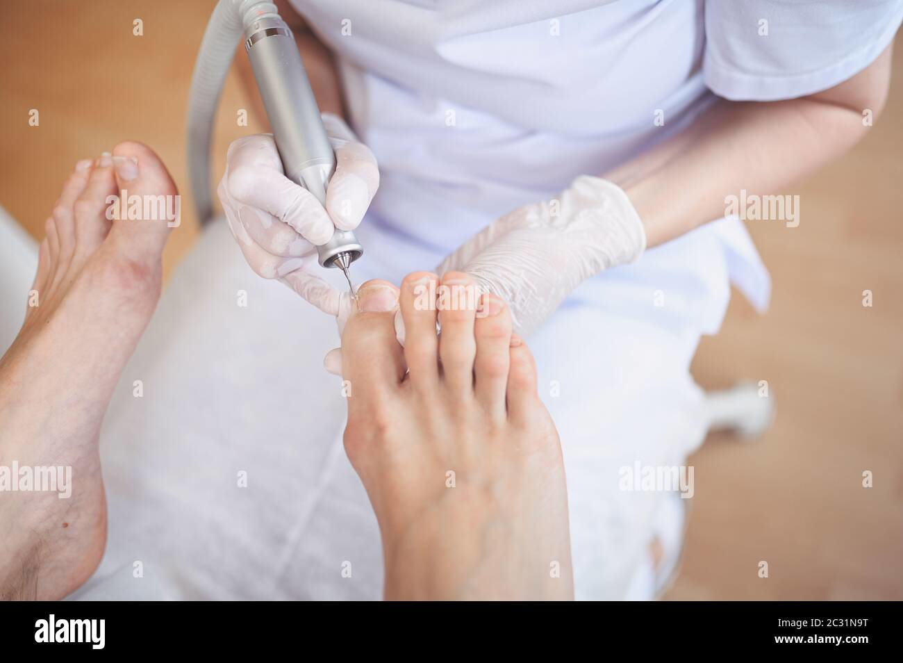 Medical professional performing hardware pedicure with nail file drill on toenails