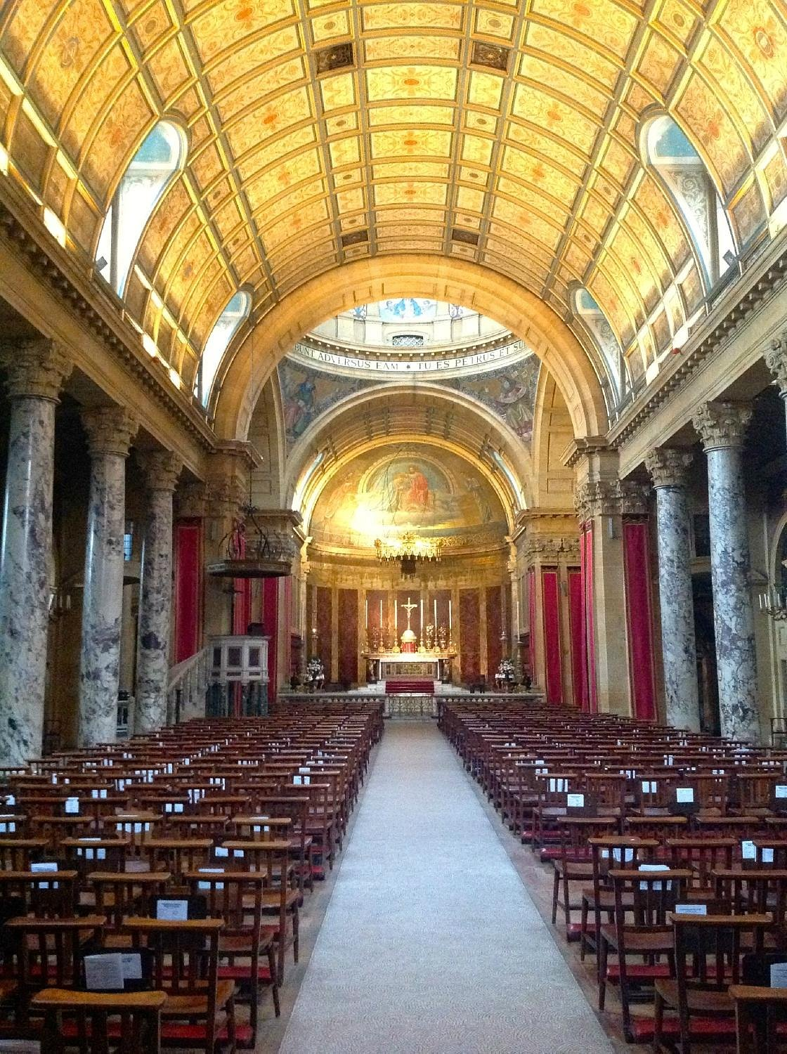 Interior of Birmingham Oratory church with its ornate arched ceiling and marble columns leading to the altar