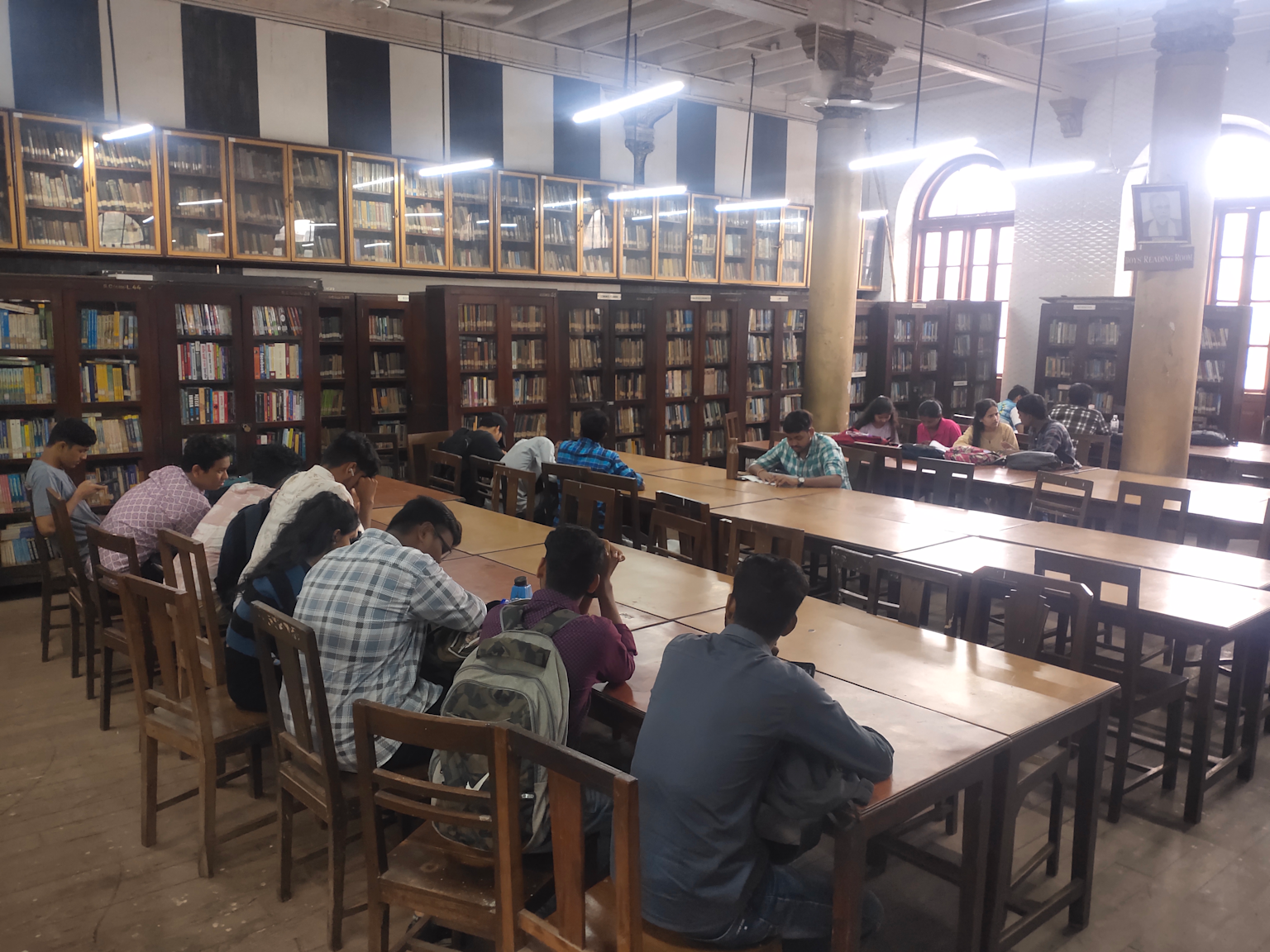 Library interior at Siddharth College Mumbai with students studying among extensive bookshelves