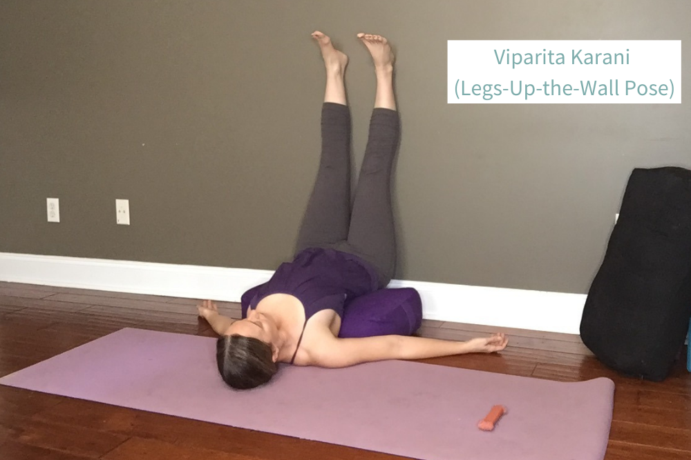 Woman practicing Viparita Karani (Legs-Up-the-Wall Pose) supported by a yoga bolster for relaxation