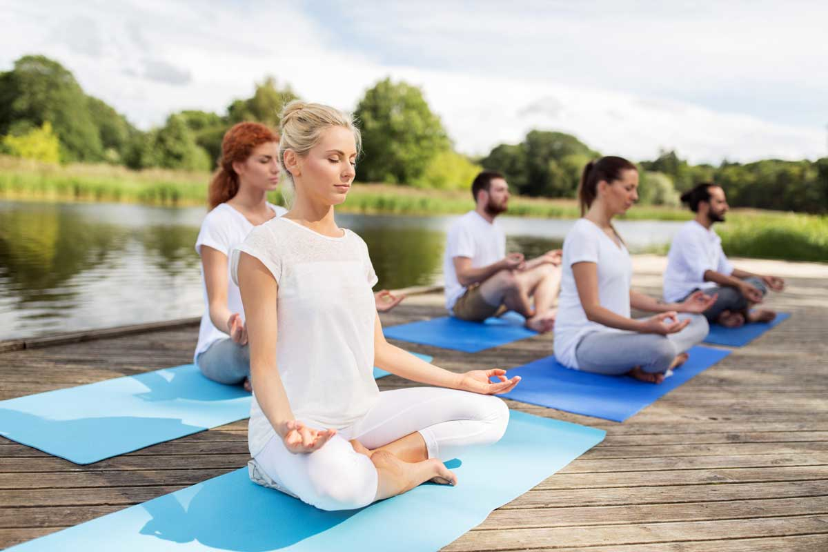 People wearing white clothing meditating outdoors in a group during a Kundalini yoga session