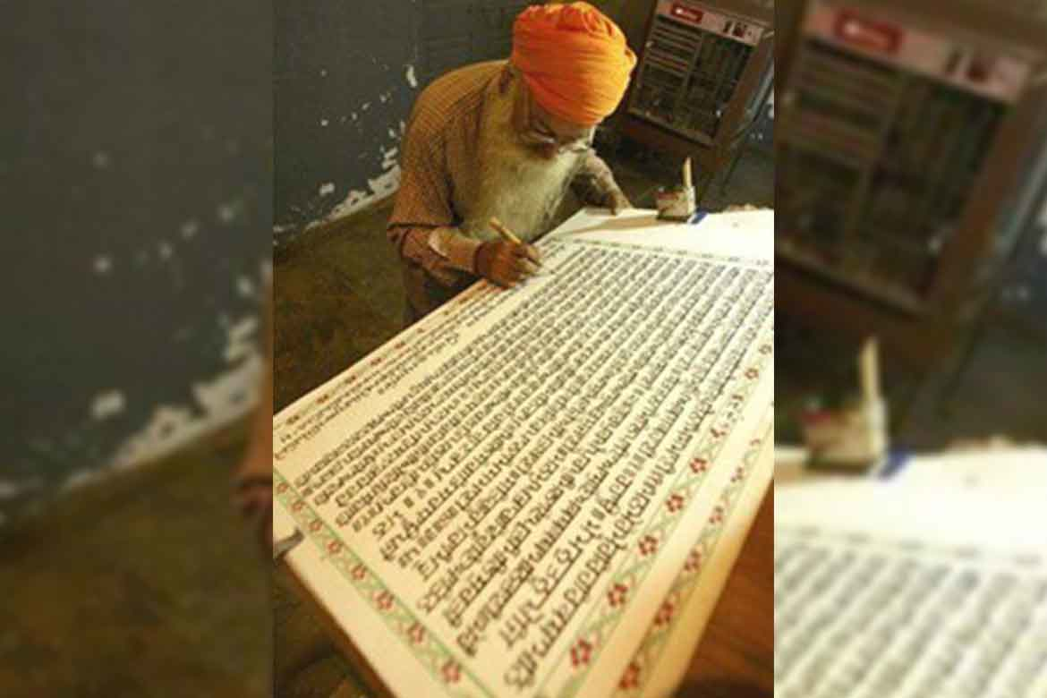 A scribe writing Guru Granth Sahib scripture featuring hymns by Sant Ravidas