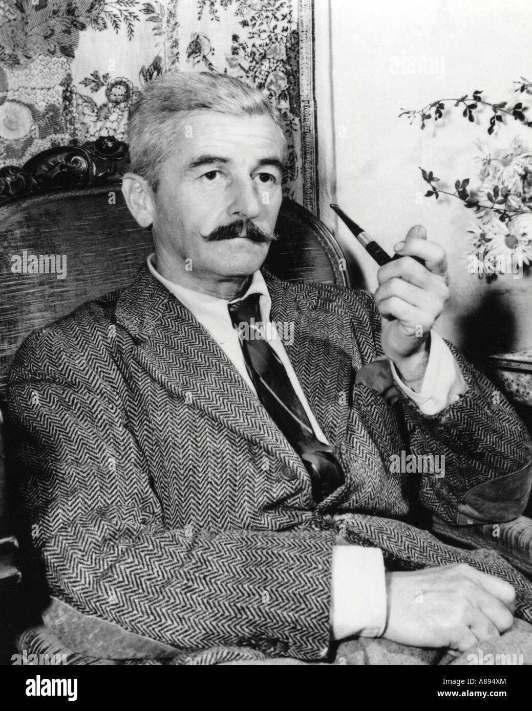 Portrait of William Faulkner, American modernist author, holding a pipe and dressed in a herringbone suit jacket