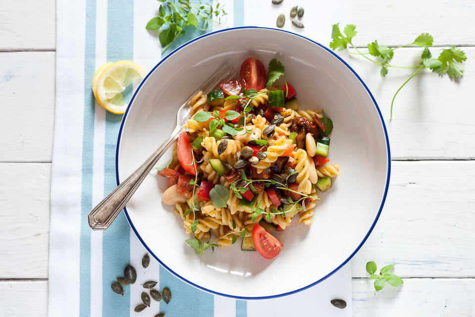 A vibrant pasta salad photographed with contrasting colors and thoughtful composition on a white and blue background.