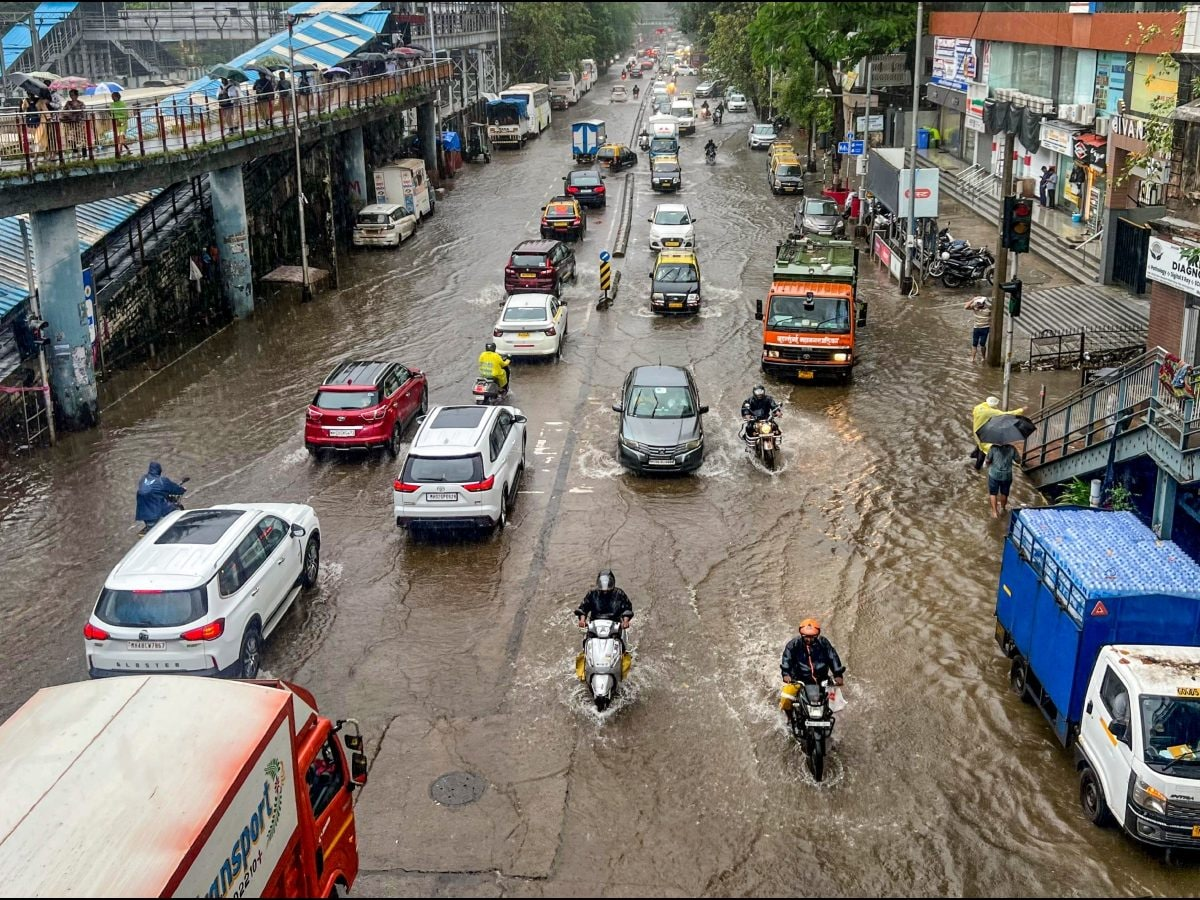 Mumbai street heavily waterlogged during monsoon rains with vehicles navigating through floodwater