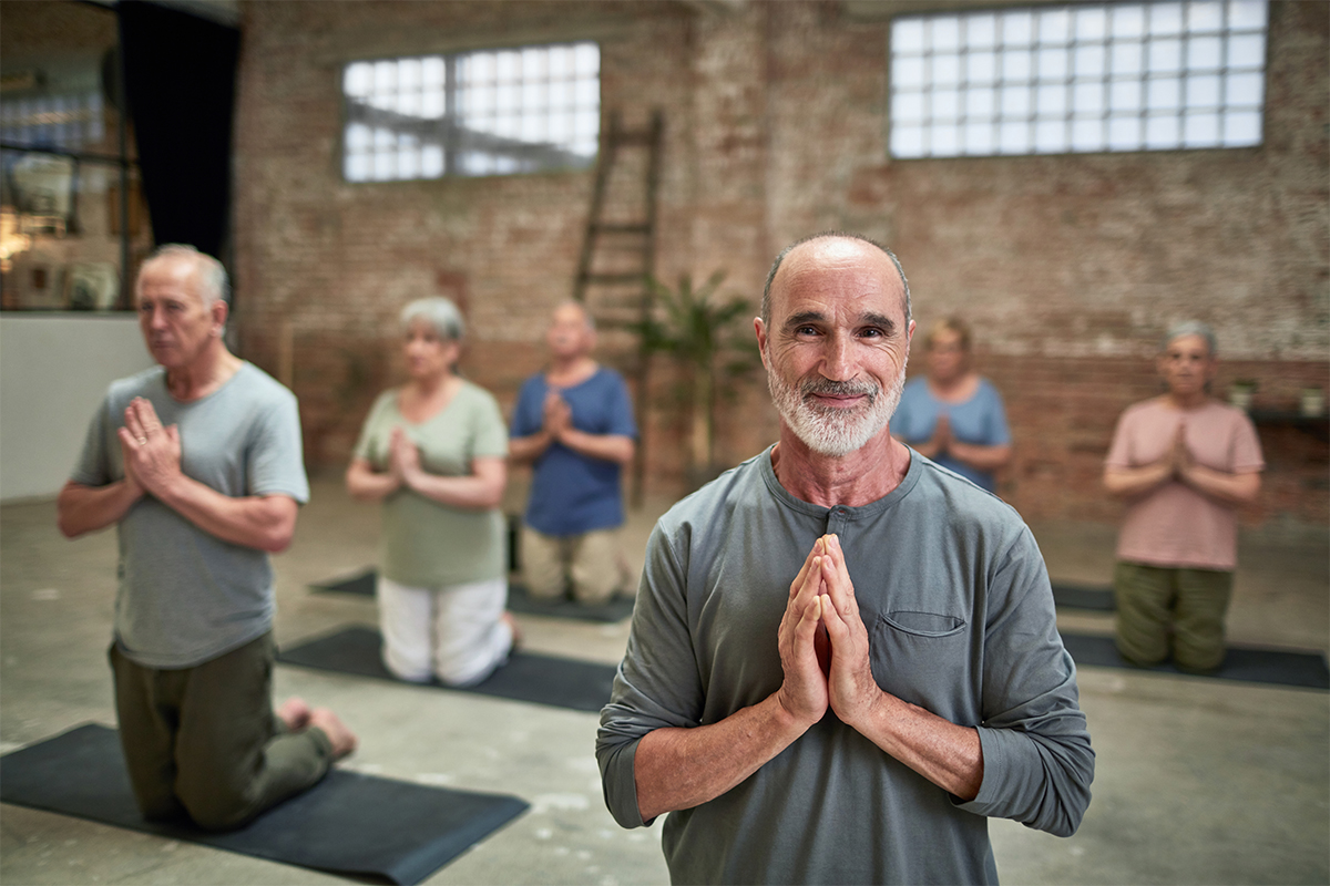 Elderly individuals practicing yoga in a serene indoor setting to promote health and mindfulness