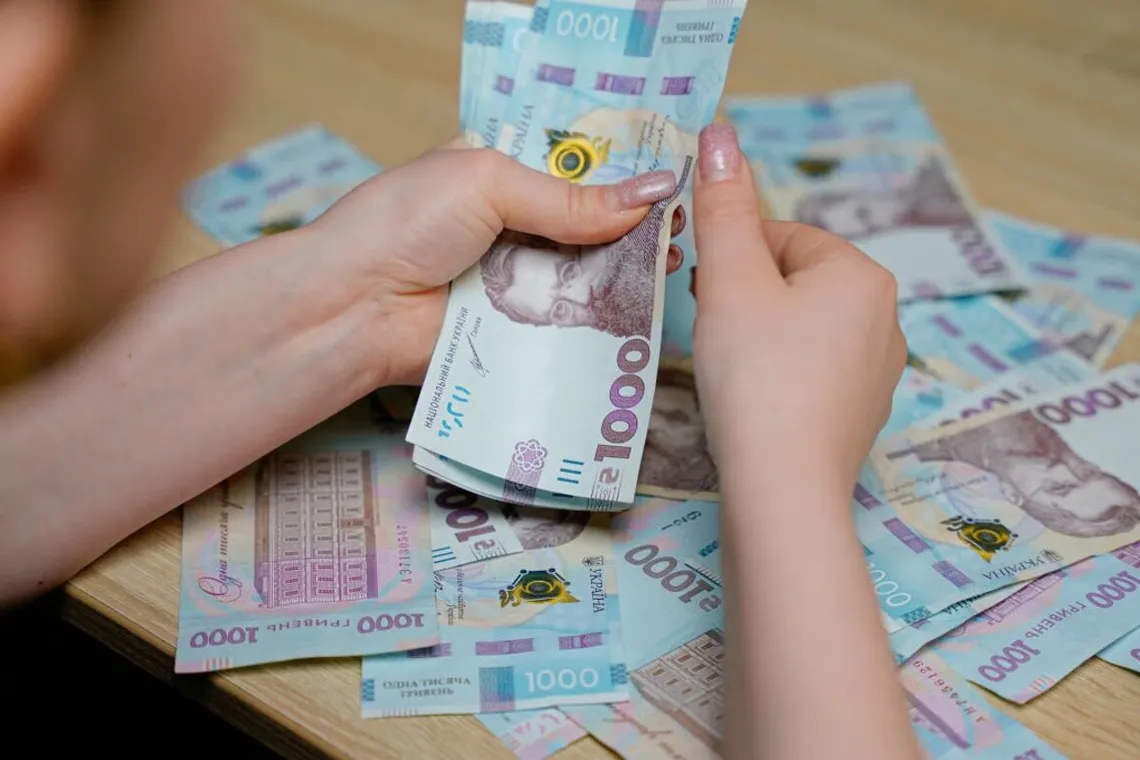 Person counting Ukrainian 1000 hryvnia banknotes representing financial matters in Ukraine