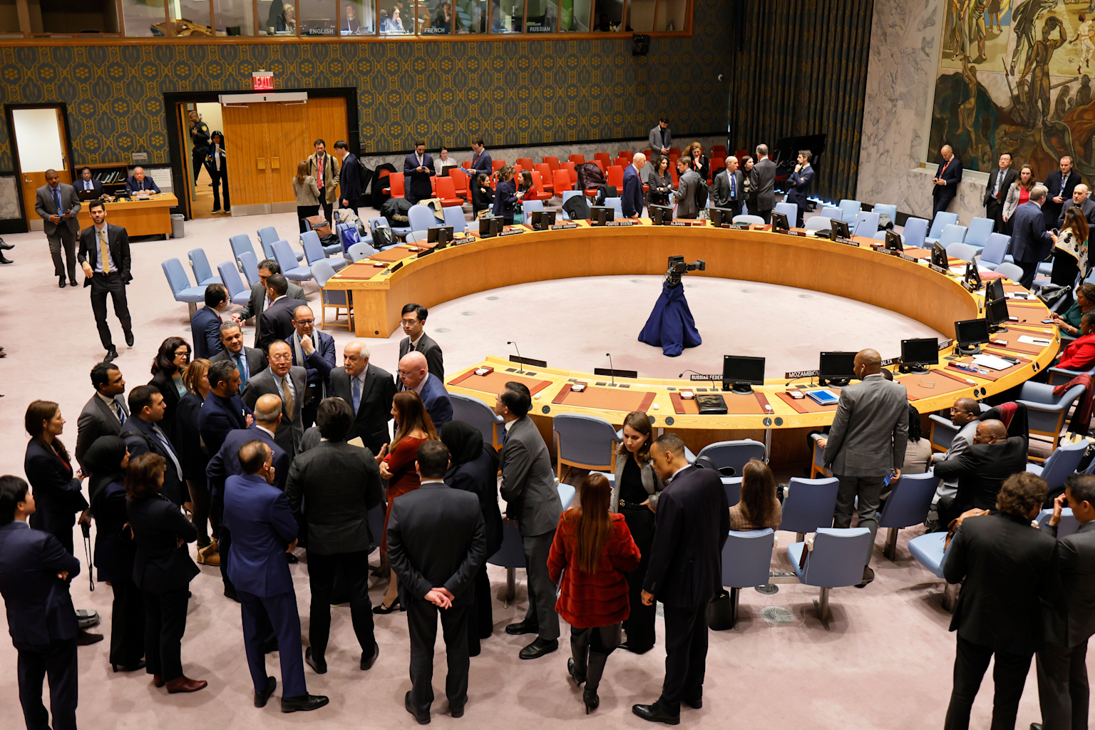 A view inside the United Nations Security Council chamber with diplomats engaging in discussions around the horseshoe-shaped desk setup