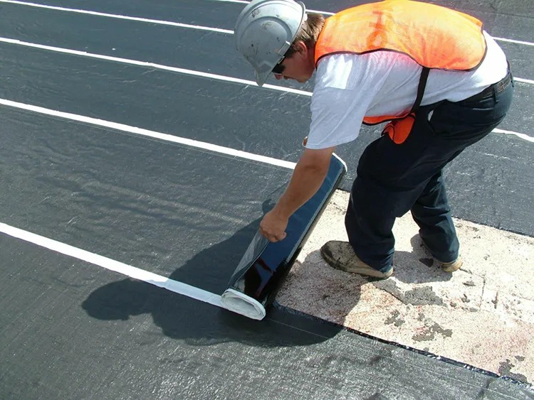 Construction worker applying waterproof membrane on building surface