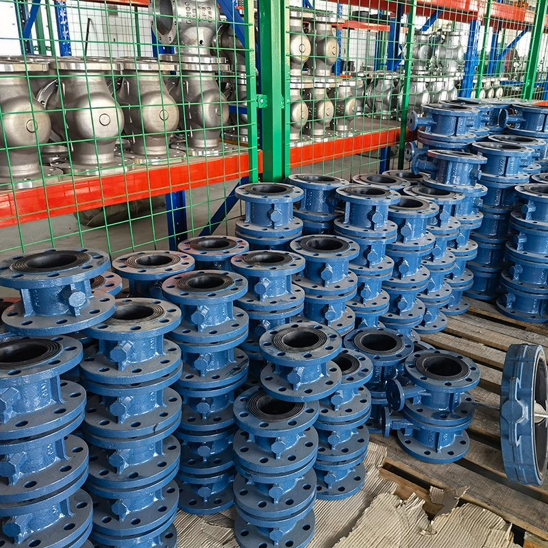Stacks of blue butterfly valve bodies in a manufacturing facility showing the raw components used in valve assembly