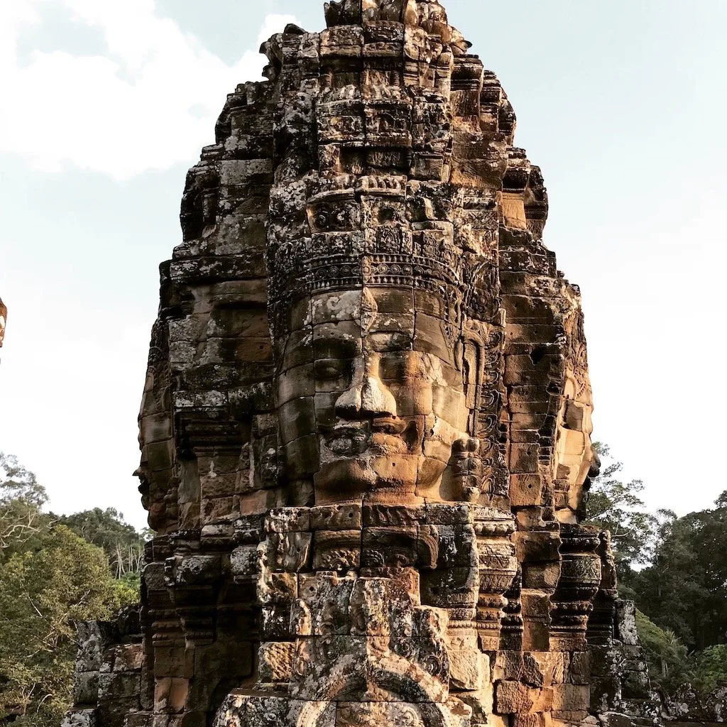 Stone faces carved into the Bayon temple at Angkor Thom, Cambodia, showcasing ancient Khmer artistry and cultural heritage