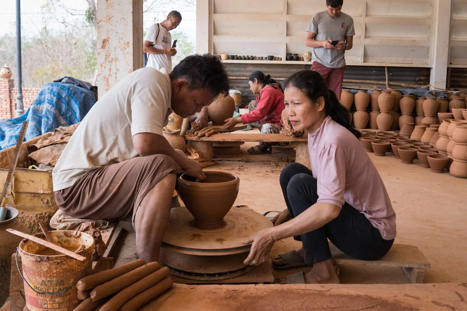 Artisans creating traditional pottery by hand in a rustic Cambodian pottery village workshop, showcasing cultural craftsmanship
