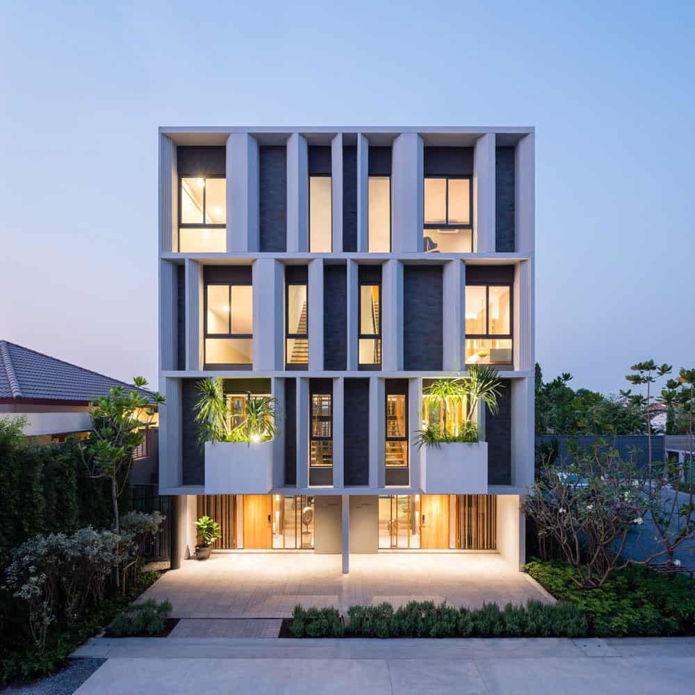 A contemporary 3-story townhouse villa with modern architecture and illuminated interiors at dusk