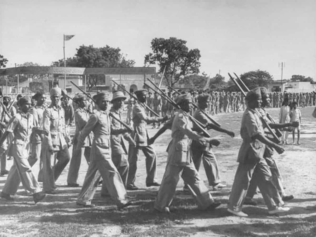 Historical black and white photo showing uniformed soldiers marching with rifles during a militant movement